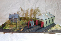 Model train layout with buildings and tracks on a textured surface