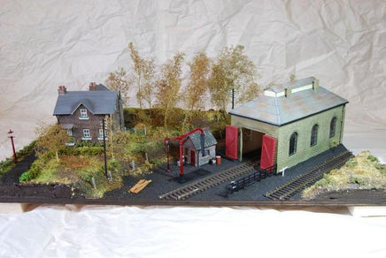 Model train layout with buildings and tracks on a textured surface