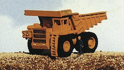 Model of a large dump truck with a person for scale on a plain background