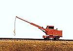 Model train crane on a track with a plain background