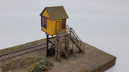 Model of a small wooden tower with a yellow top on a white background