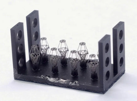 3D-printed metal components on a black holder against a white background