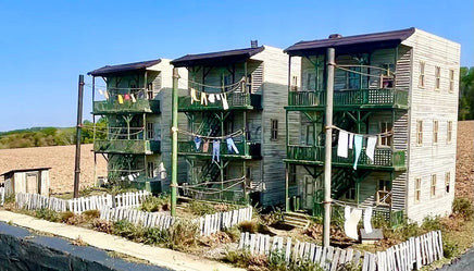 Multistory apartment building with laundry hanging on lines against a clear blue sky.
