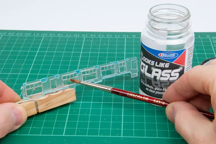 Model train track with a brush and 'Looks Like Glass' product on a green cutting mat.