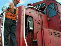 Person in safety vest standing next to a red train engine with the number 126.