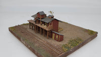 Model of a wooden cabin and platform on a miniature landscape with tracks.
