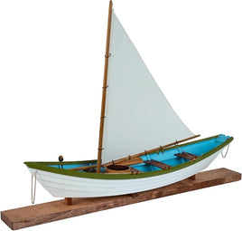 Model sailboat with white sail and green hull on a wooden stand against a white background