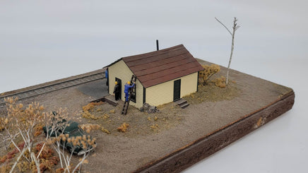 Model of a small house with a car and people on a miniature landscape