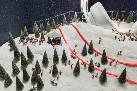 Model of a snowy landscape with trees, a gazebo, and people on a hillside.