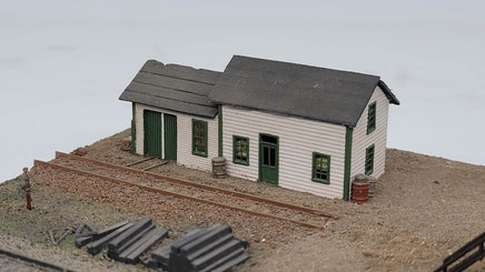 Model train station with tracks and scenery on a plain background