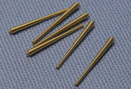 Set of six brass pins on a textured gray surface