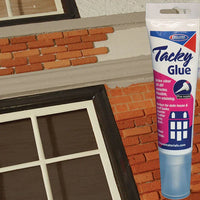 Tube of Elmer's Tacky Glue next to a miniature model of a window and brick wall.