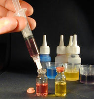 Person using a syringe to transfer liquid from a bottle into other containers with a dark background.