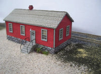 Model of a red building with a gray roof on a textured surface