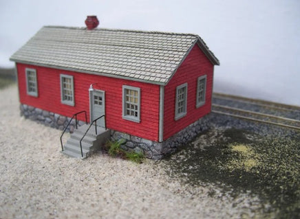 Model of a red building with a gray roof on a textured surface