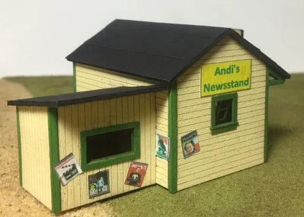 Model of a newsstand with a sign reading 'Andi's Newsstand' on a neutral background