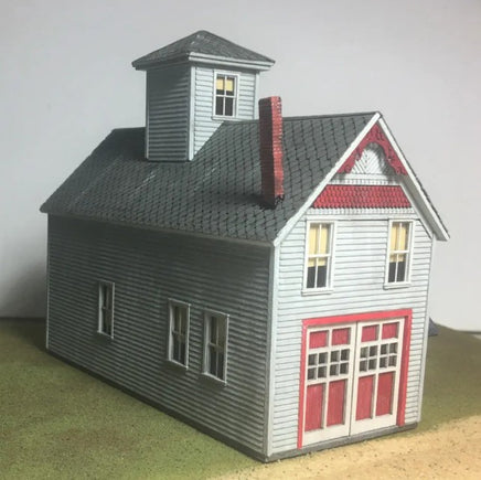 Model of a two-story house with a gray roof and red accents on a green base.