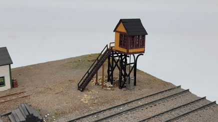 Model train station with a small building and staircase on a plain background