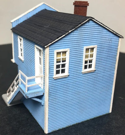 Model of a blue house with a black roof on a dark surface