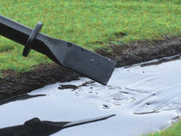 Black garden tool being used to smooth out a white substance on grass