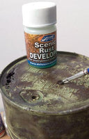 Deluxe Scenic Rust Developer bottle on a rusty metal surface with a brush.