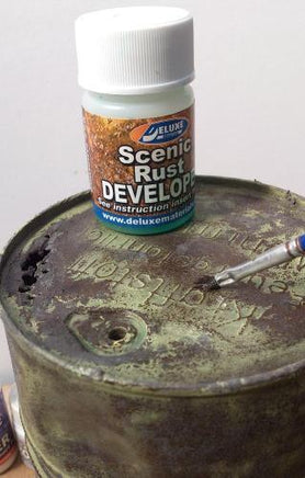 Deluxe Scenic Rust Developer bottle on a rusty metal surface with a brush.