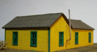 Model of a yellow building with green windows on a plain background