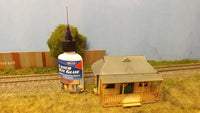 Bottle of Elmer's Laminating Kit Glue with a model house and track in the background