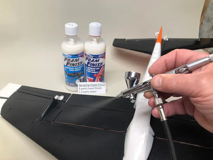 Person using a spray gun with foam finish bottles in the background