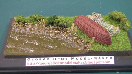 Model of a boat on a miniature landscape with 'George Dent Model Maker' label.