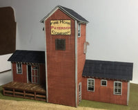 Model of a fire hose company building with a sign on a plain background