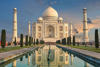 The Taj Mahal with a reflection in a pool, surrounded by greenery