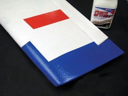 White and blue foam roller with a red patch on a black surface, next to a bottle of Foam Armour.