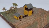 Model train layout with small buildings and tracks on a white background