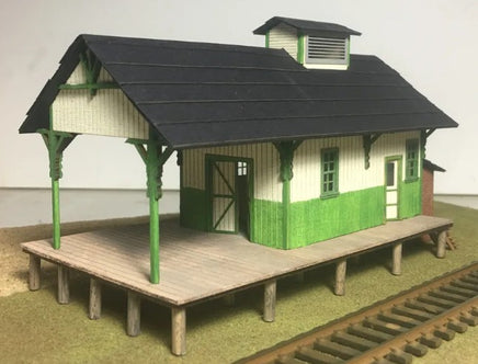 Model train station with green and brown colors on a plain background