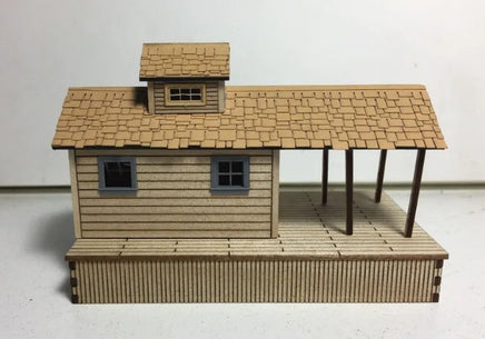 Model of a small wooden cabin with a shingled roof on a white background