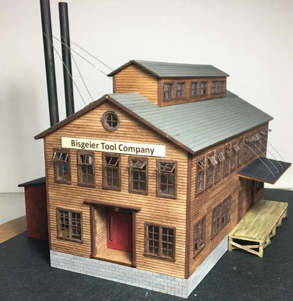 Model of a wooden building with 'Bisgeier Tool Company' sign on a gray background