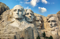 Stone carvings of four伟人的 faces on Mount Rushmore with a blue sky and clouds in the background.