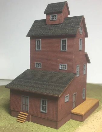Model of a two-story red brick building with a gray roof on a plain background