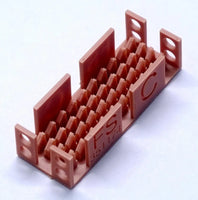 Red plastic component with cut-out patterns and text on a white background