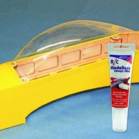 Model airplane canopy with a tube of RC Modellers Canopy Glue on a blue background