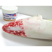 White surfboard with red and white pattern next to a container labeled 'Wonderfill'.