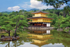 Traditional Japanese building with gold facade reflected in a pond surrounded by trees