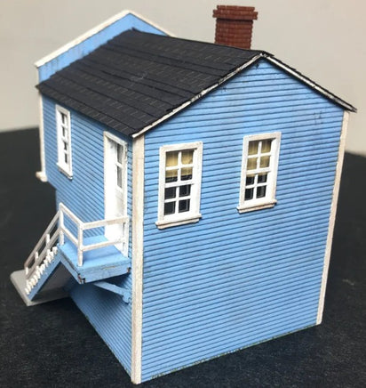 Model of a blue house with a black roof on a dark surface
