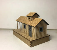 Model of a small wooden cabin with a shingled roof on a white background