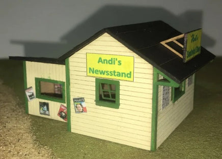 Model of a newsstand with 'Andi's Newsstand' sign on a neutral background