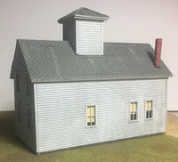 Model of a two-story building with a gray roof and white walls on a neutral background