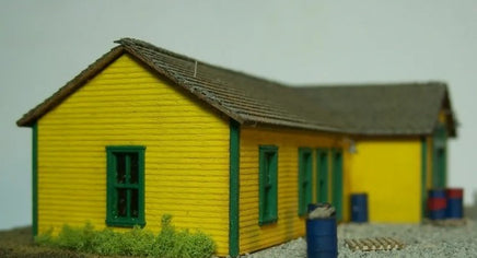 Model of a yellow building with green trim on a plain background