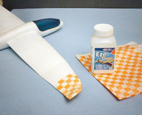 Eze Dope bottle on a checkered cloth with a white object and blue tool in the background.
