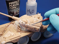 Model tank being worked on with putty and water bottle in the background